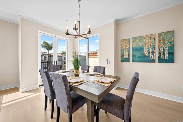 dining area with a chandelier, ornamental molding, light wood-style floors, and baseboards