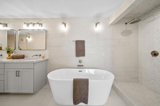 full bath featuring tile walls, walk in shower, a soaking tub, and vanity