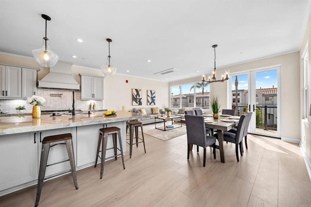 dining room with a chandelier, crown molding, recessed lighting, and light wood-style flooring