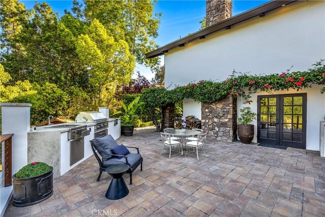 view of patio with exterior kitchen, a grill, french doors, and outdoor dining space