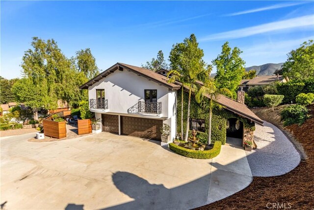 view of side of property featuring a balcony, an attached garage, and stucco siding