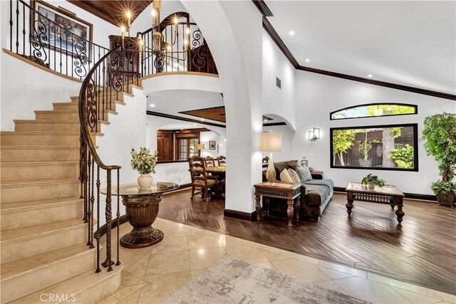tiled foyer with arched walkways, a towering ceiling, crown molding, recessed lighting, and stairway
