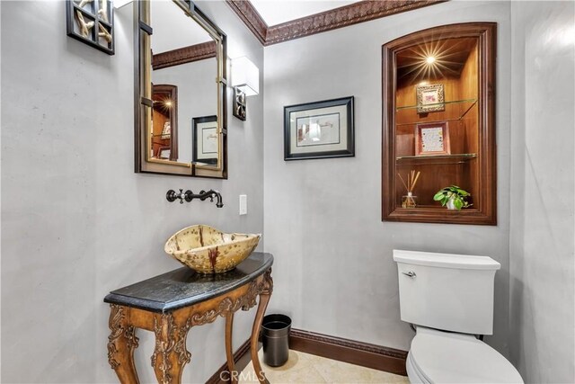 bathroom featuring a sink, toilet, baseboards, and tile patterned floors