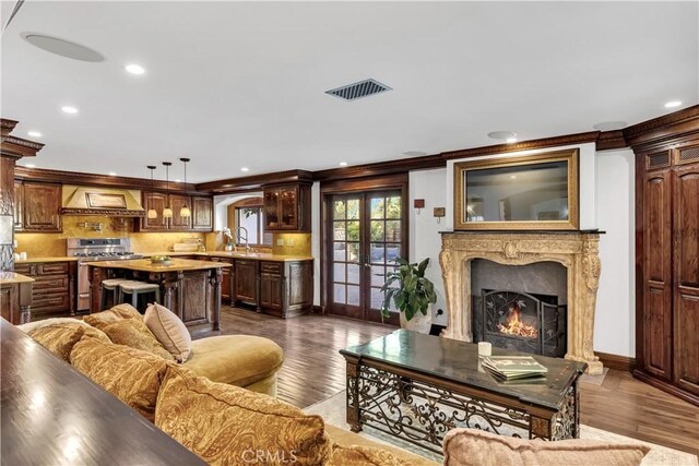 living room with dark wood-style flooring, a premium fireplace, ornamental molding, and recessed lighting