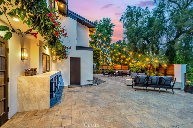 patio terrace at dusk featuring an outdoor hangout area and fence