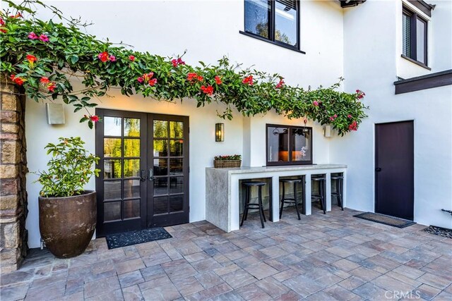 view of exterior entry with french doors, a patio, and stucco siding