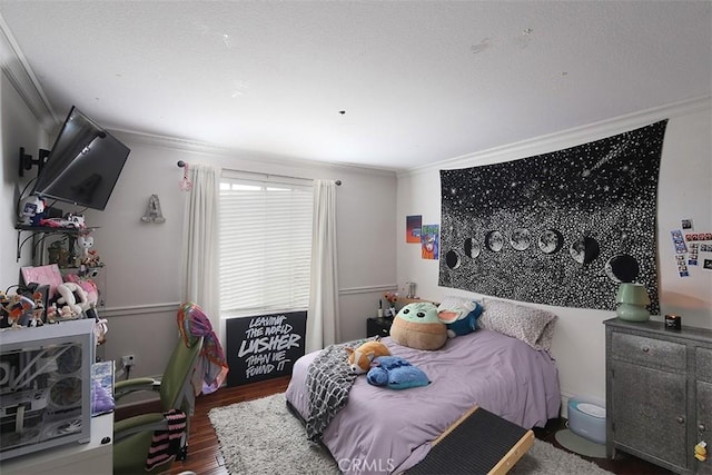 bedroom with ornamental molding and wood finished floors