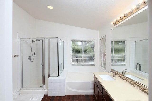 bathroom featuring vaulted ceiling, a garden tub, a stall shower, double vanity, and wood finished floors