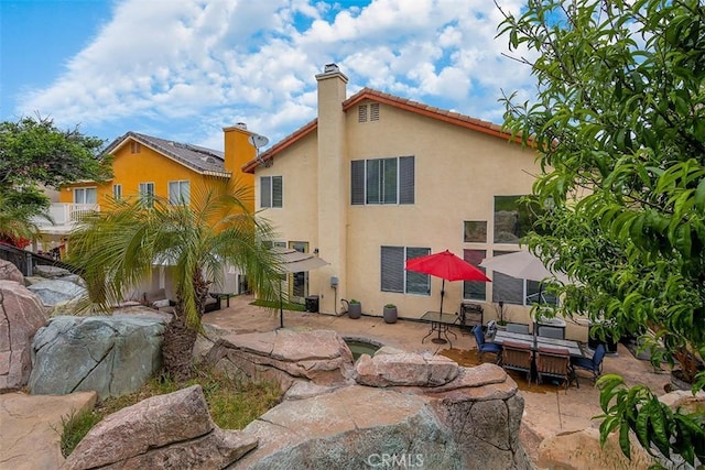 back of property with a chimney, a patio, and stucco siding
