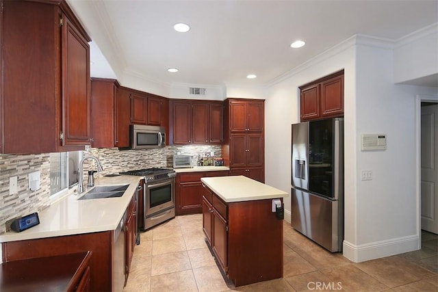 kitchen with appliances with stainless steel finishes, a sink, backsplash, a center island, and light countertops