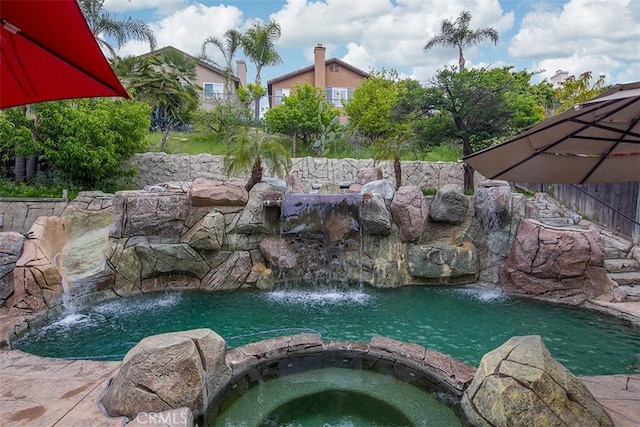 view of pool featuring a garden pond and a pool with connected hot tub