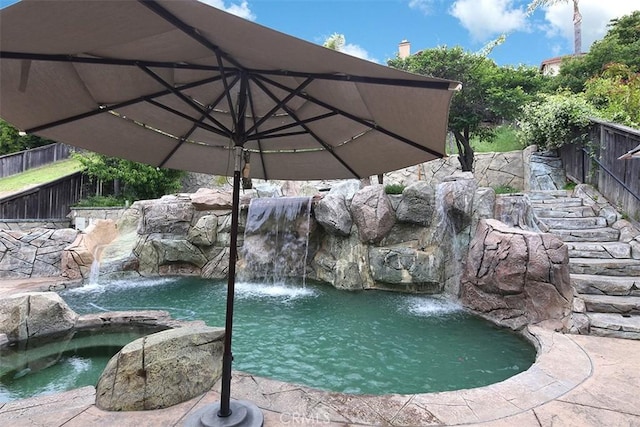 view of swimming pool with fence and a garden pond