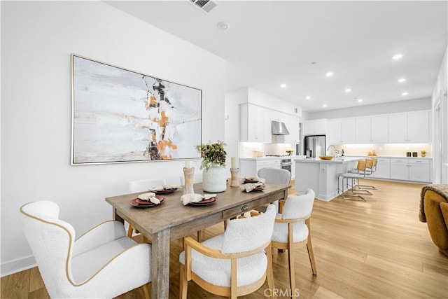 dining space with light wood-style floors and recessed lighting
