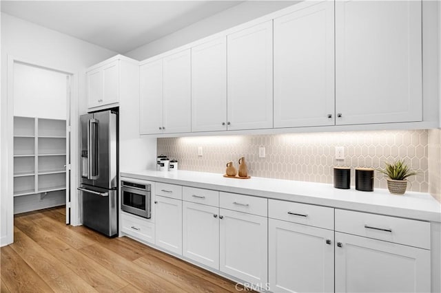 kitchen featuring high end refrigerator, wall oven, light countertops, and white cabinetry