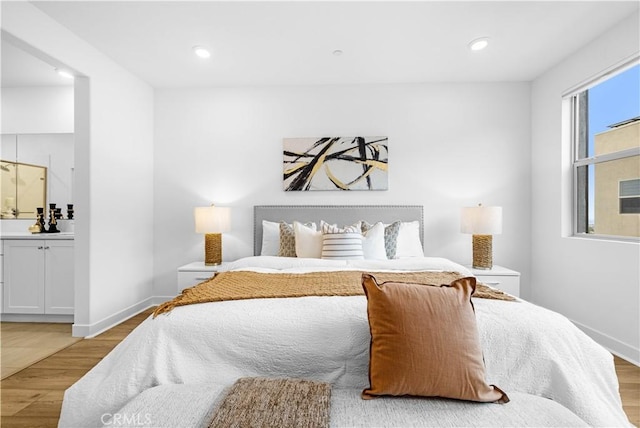 bedroom with baseboards, light wood finished floors, recessed lighting, and connected bathroom