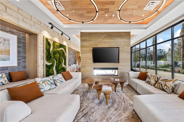 living room featuring a tray ceiling, wood walls, wood ceiling, and a fireplace