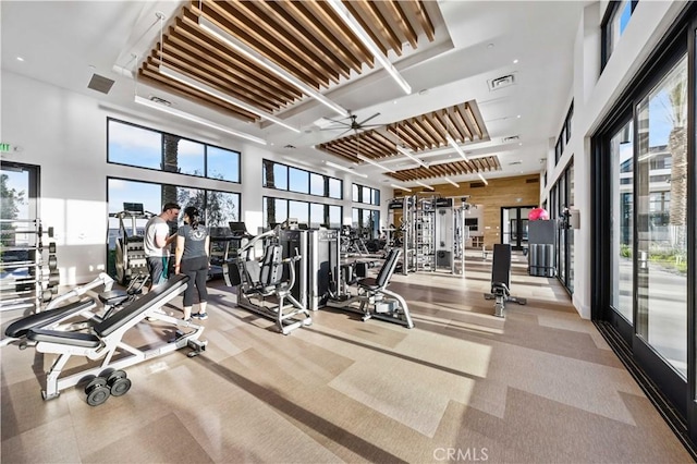 exercise room featuring a ceiling fan and a high ceiling