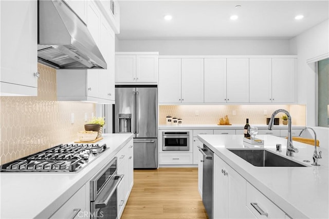 kitchen with under cabinet range hood, stainless steel appliances, a sink, light countertops, and white cabinets