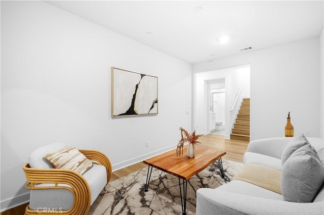 living area featuring wood finished floors, baseboards, and stairs