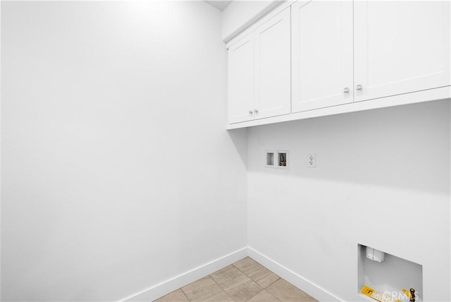 clothes washing area with cabinet space, baseboards, and washer hookup
