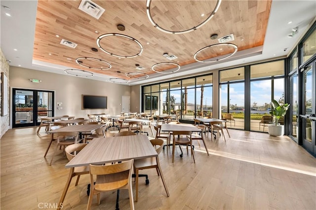 dining space with a tray ceiling, wooden ceiling, expansive windows, healthy amount of natural light, and light wood-type flooring