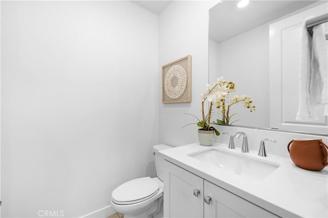 bathroom featuring toilet, vanity, and baseboards