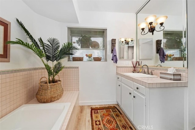 full bath featuring vanity, a bath, a chandelier, and wood finished floors