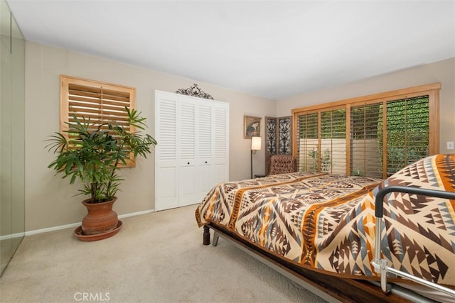 carpeted bedroom featuring baseboards and a closet