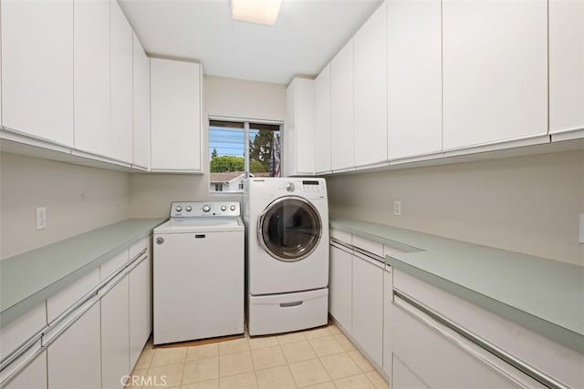 laundry room featuring washing machine and dryer, cabinet space, and light tile patterned floors