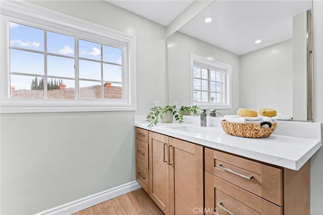 bathroom featuring wood finished floors, baseboards, vanity, and recessed lighting