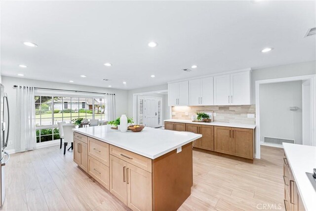 kitchen featuring light countertops, tasteful backsplash, recessed lighting, a center island, and light wood finished floors