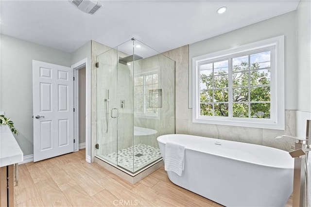 bathroom featuring a shower stall, a freestanding bath, wood finished floors, and recessed lighting