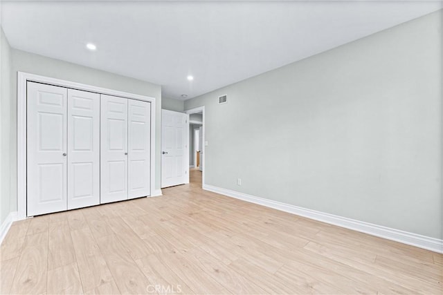 unfurnished bedroom featuring baseboards, light wood-style flooring, a closet, and recessed lighting