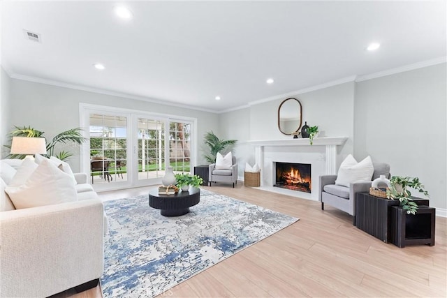 living area with a fireplace with flush hearth, light wood-style floors, recessed lighting, crown molding, and baseboards