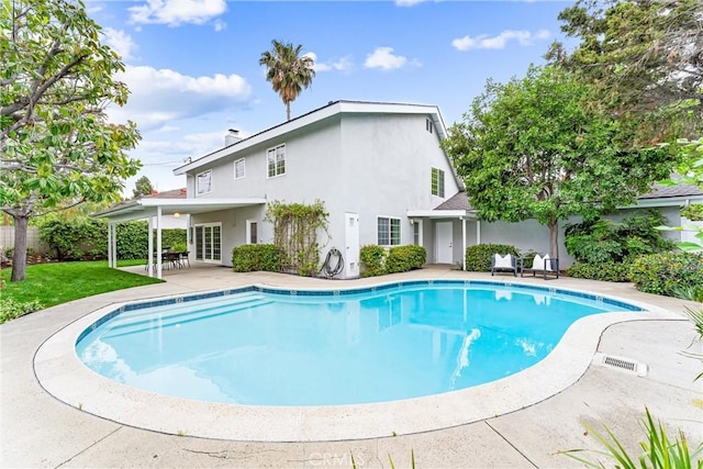 outdoor pool with a patio area and a yard