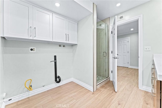 laundry room featuring hookup for a gas dryer, light wood finished floors, hookup for an electric dryer, cabinet space, and baseboards