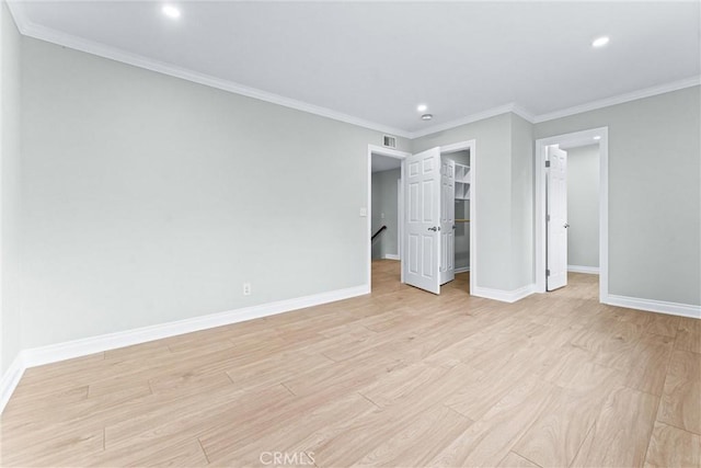 unfurnished bedroom featuring recessed lighting, baseboards, light wood-style flooring, a walk in closet, and ornamental molding
