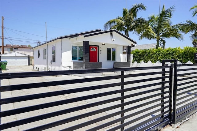 view of front of property with a fenced front yard, stucco siding, and an outbuilding