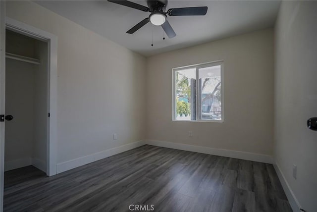 unfurnished bedroom featuring wood finished floors, baseboards, a closet, and ceiling fan