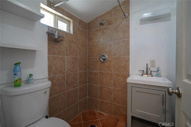 bathroom featuring tiled shower, toilet, vanity, and a textured ceiling