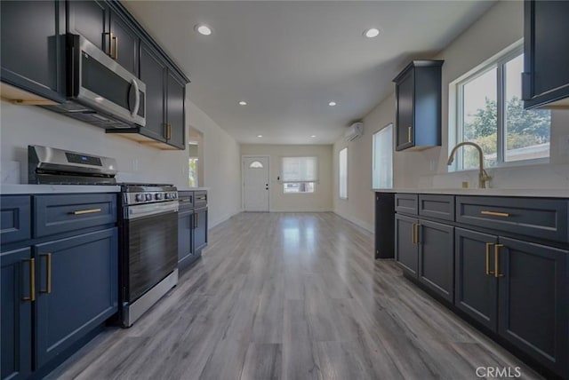 kitchen featuring appliances with stainless steel finishes, light wood-style floors, a sink, light countertops, and recessed lighting