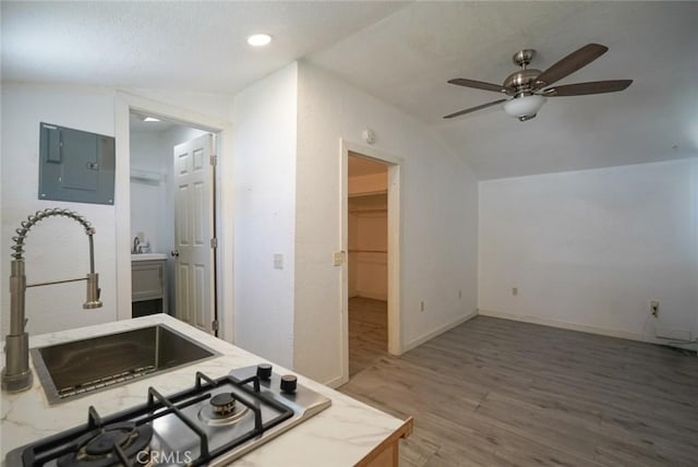 kitchen with vaulted ceiling, electric panel, ceiling fan, wood finished floors, and stainless steel gas stovetop