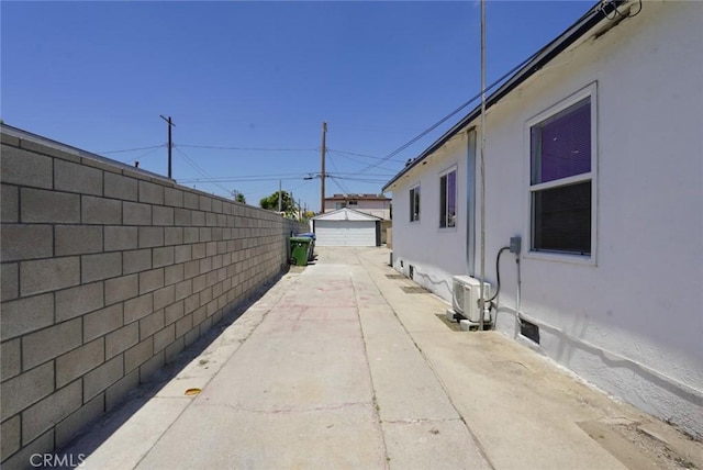 view of home's exterior with stucco siding, fence, a detached garage, and a cooling unit