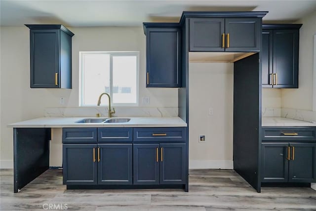 kitchen with a sink, light wood-style flooring, and baseboards
