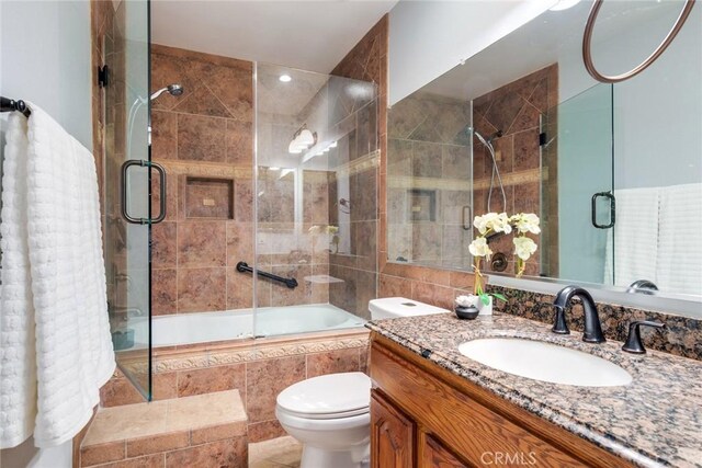 bathroom featuring toilet, vanity, tile walls, tiled shower / bath, and tile patterned floors
