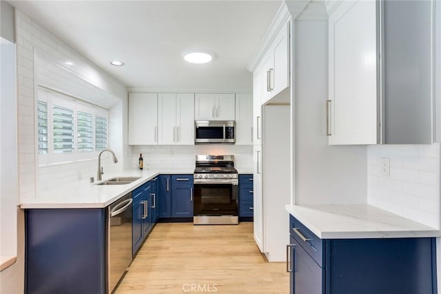 6199 Cabernet Pl, Rancho Cucamonga, CA 91737 - kitchen featuring appliances with stainless steel finishes, blue cabinetry, light wood-type flooring, a sink, and backsplash