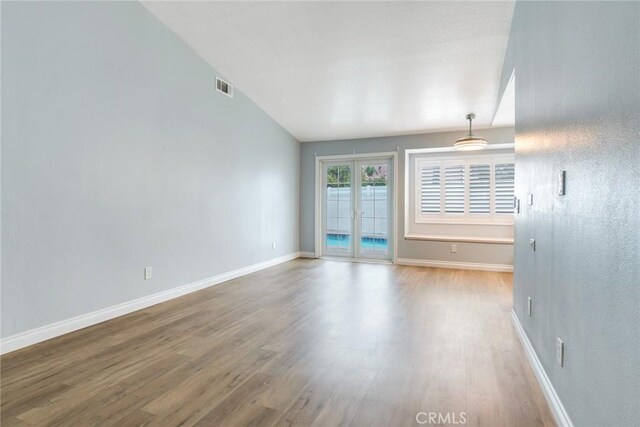 spare room featuring wood finished floors, baseboards, and french doors