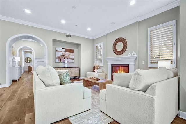 135 Bridle Path, Irvine, CA 92602 - living room featuring ornamental molding, recessed lighting, wood finished floors, a glass covered fireplace, and arched walkways