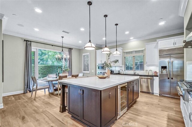 135 Bridle Path, Irvine, CA 92602 - kitchen with appliances with stainless steel finishes, wine cooler, white cabinetry, light wood-style floors, and crown molding
