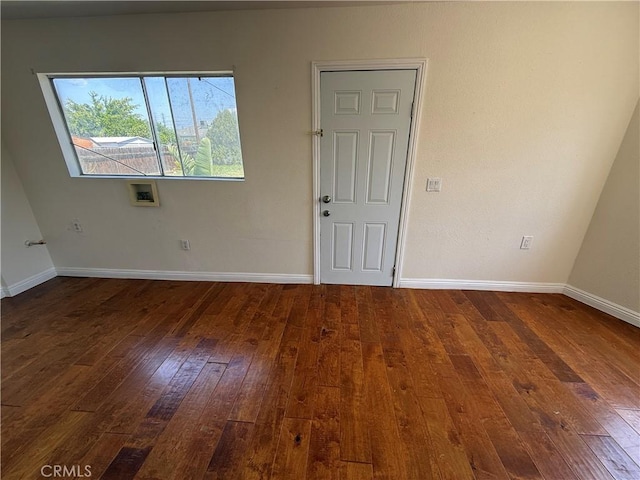 spare room featuring dark wood-type flooring and baseboards